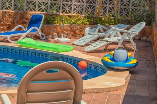 Luxury swimming pool with beautiful landscaping of the territory. In the background a Mediterranean wall decorated with sandstones.