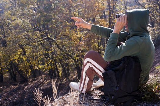The mountaineer shows at something far away, while looks away with binoculars.