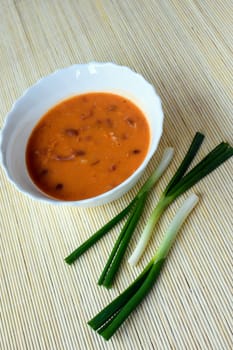 Bowl of beans with spring onions is on natural background.