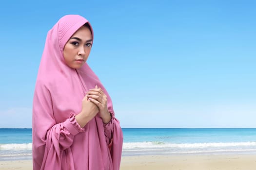 Portrait of asian muslim woman with hijab praying to god on the beach