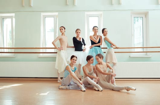 Thr seven ballerinas at ballet rack in the rehearsal hall of the theater
