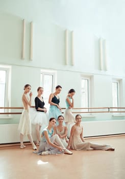 Thr seven ballerinas at ballet rack in the rehearsal hall of the theater