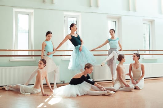 Thr seven ballerinas at ballet rack in the rehearsal hall of the theater