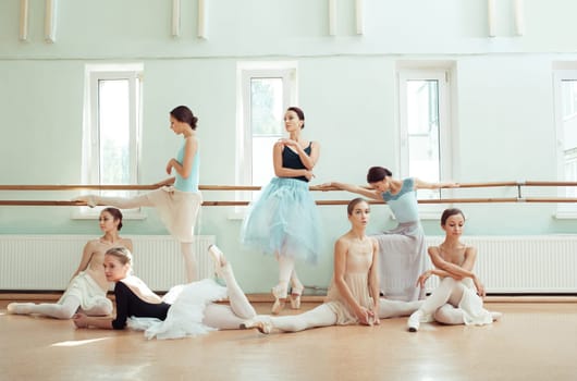 Thr seven ballerinas at ballet rack in the rehearsal hall of the theater