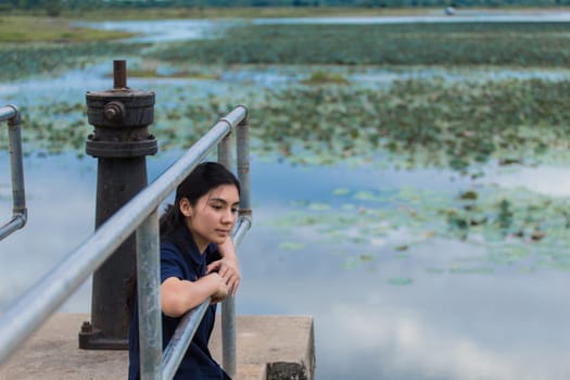 Young beautiful Asian girl sitting on jetty forest and river on background