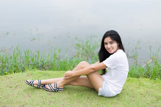 Asian woman is sitting on the rock in the park