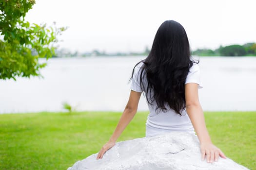 Asian woman is sitting on the rock in the park