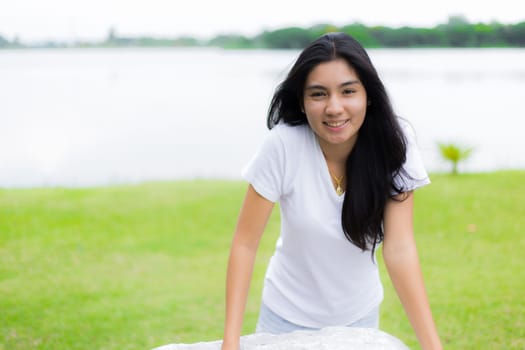Asian woman is sitting on the rock in the park