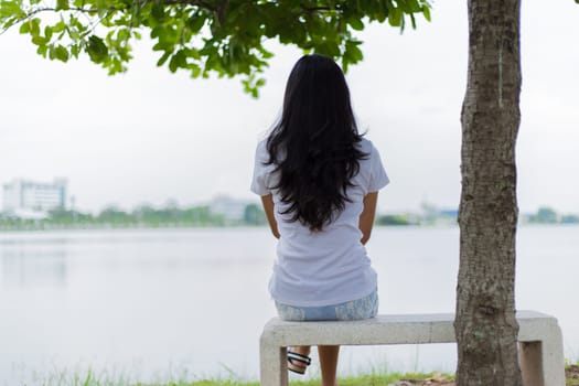 Asian woman is sitting on the rock in the park