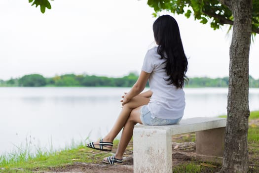 Asian woman is sitting on the rock in the park