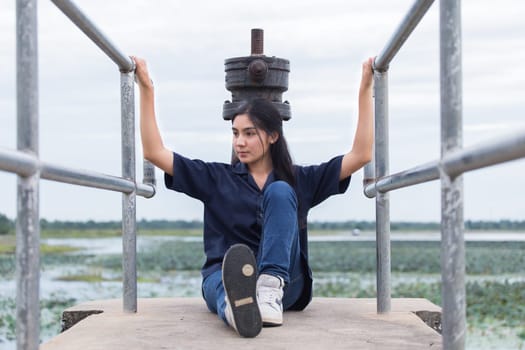 Young beautiful Asian girl sitting on jetty forest and river on background