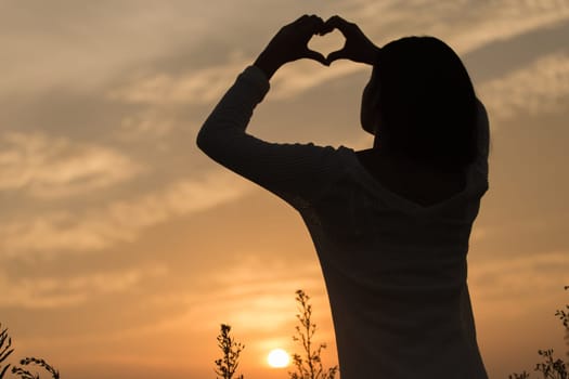 Silhouette of a young asian woman enjoying flowers and nature sunset