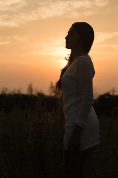 Silhouette of a young asian woman enjoying flowers and nature sunset