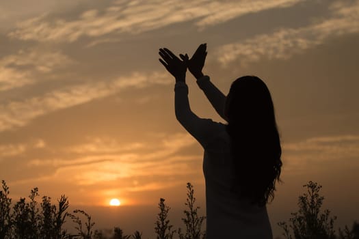 Silhouette of a young asian woman enjoying flowers and nature sunset