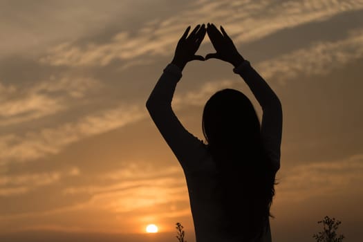 Silhouette of a young asian woman enjoying flowers and nature sunset