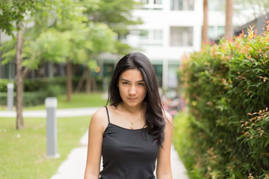 A portrait of a young asian woman walking on the park