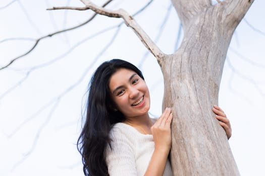 Asian woman and A bare tree with branches in corn field in evening light.