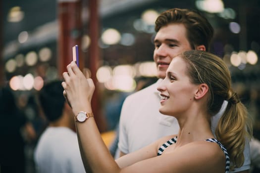 Young couple are taking tourist photos in Queen Victoria market, Australia.