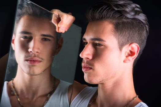 Narcissistic handsome young man admiring his reflection in the mirror in a show of self-absorption