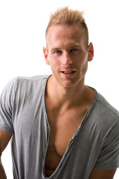 Fit male model smiling with a lot of confidence wearing grey t-shirt revealing muscular chest, looking at camera