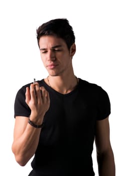 Young man disgusted by cigarette he's holding in his hand. Standing isolated on white background looking at it