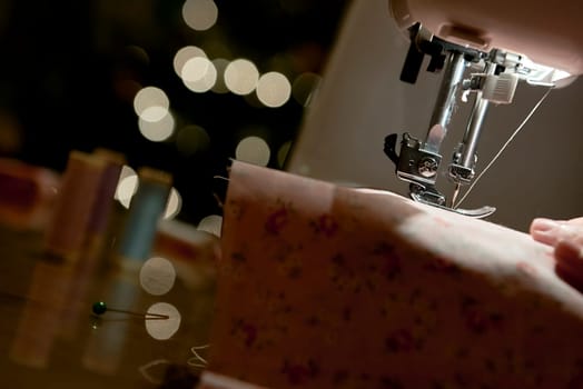 Low key detail of automatic sewing machine needle shot from the side