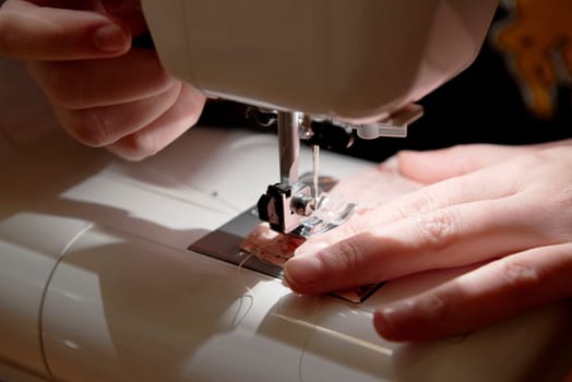 Detail of hands working on piece of fabric on automatic sewing machine