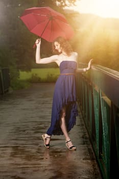 Young attractive woman with red umbrella after rain in nature