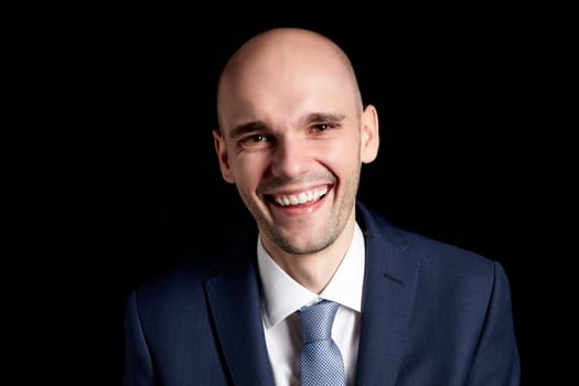 Studio portrait of young smiling man on black background.