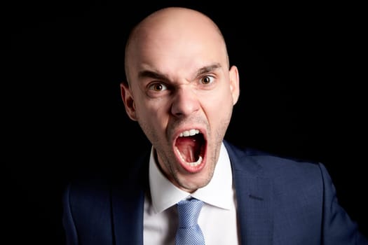Studio shot of a aggressive young businessman against black background.
