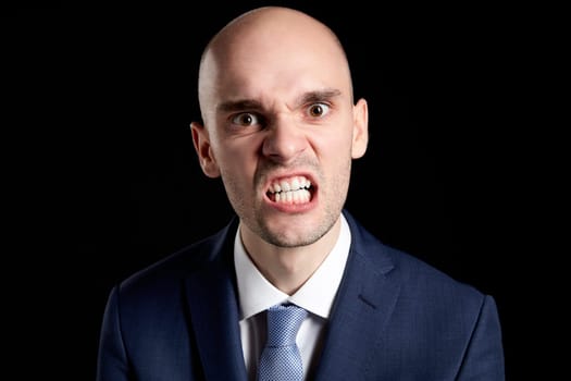 Portrait of Young Angry Guy against Black Background.