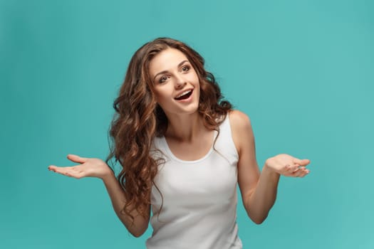 The young woman's portrait with happy emotions on blue background