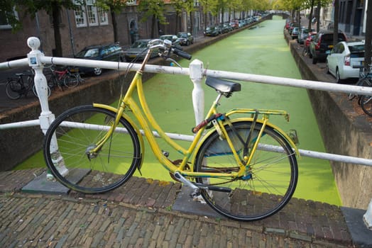 yellow bicycle parked on a bridge in the center of Delft.