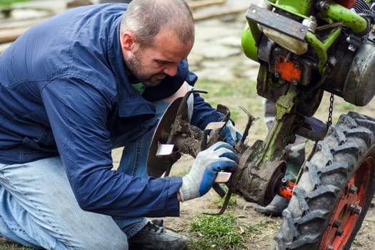The worker is repairing the agricultural machine.