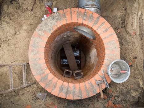 Renewal of a round sewage shaft with bricks in the shell in an open excavation pit.
