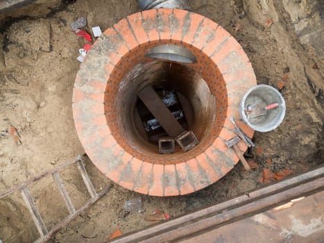 Renewal of a round sewage shaft with bricks in the shell in an open excavation pit.