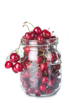 Glass jar with lid full  of cherries isolated on a white background