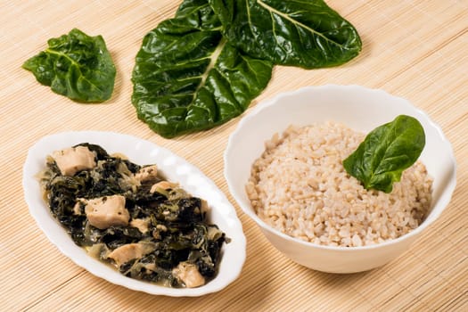 Chicken with mangold and spinach and a bowl of rice is Asian food.