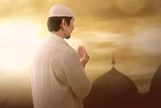 Portrait of muslim man praying to god during sunset background