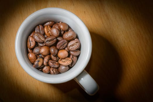 Nice cup of coffe with toasted coffee seeds inside on wood background