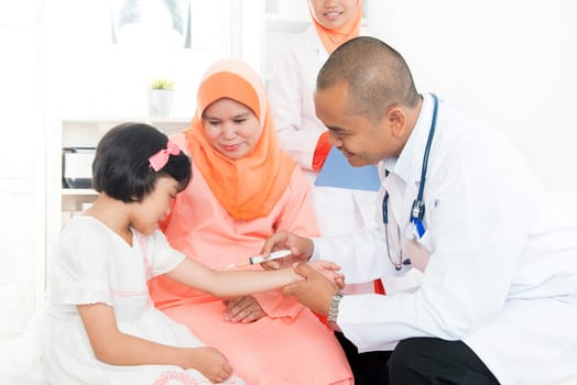 Vaccination concept.  Southeast Asian children receiving vaccine from doctor. Muslim family.