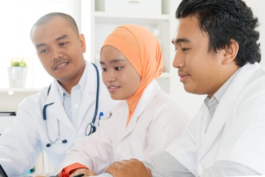 Medical team sitting and talking at the hospital. Southeast Asian Muslim doctors and nurses.