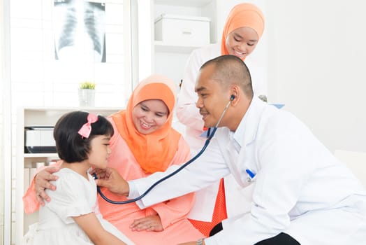 Southeast Asian child patient consulting medical doctor. Muslim family.