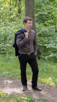portrait of young businessman in forest, trees in the background.