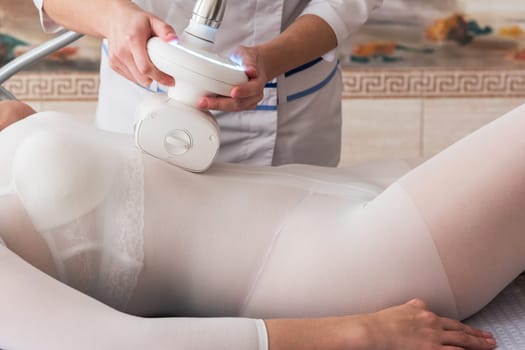 Woman in white suit getting anti cellulite massage in a beauty SPA salon. LPG, and body contouring treatment in clinic. Lipomassage procedure on female body. Body care.