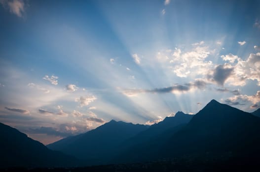 The sun setting behind the mountains of South Tyrol shines on individual clouds in the evening sky.