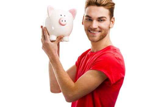 Handsome young holding a piggybank and smiling, isolated over a white background