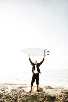 A Businessman holding is surfboard after a long day of work