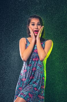 Young beautiful woman with splash of rain. Studio shot