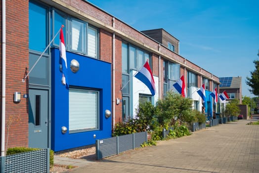 residential neighborhood with dutch flags hanging outside during a national holiday